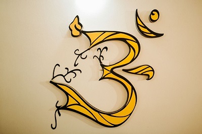 Símbolo Om decorativo en tonos dorados y negros sobre una pared clara